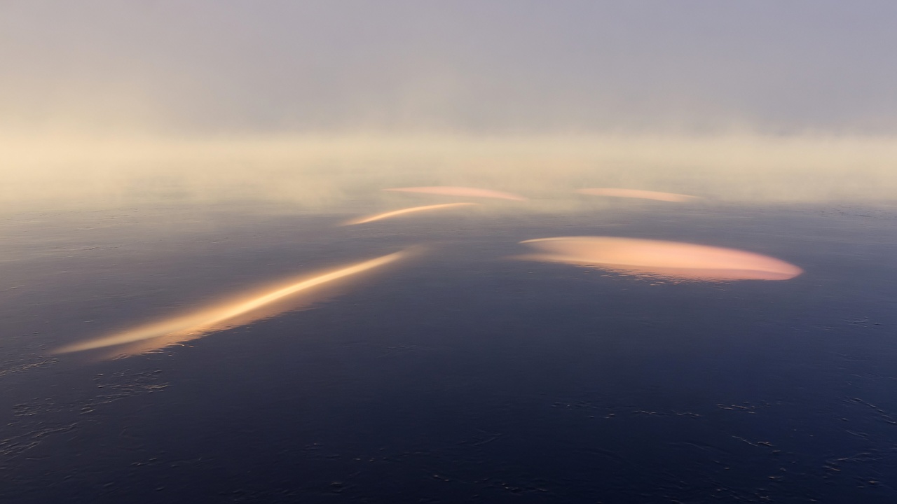 Soft arcs of light over still water at dawn
